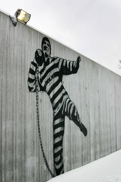 Graffiti Art by Dolk within the prison walls showing prisoner trying to throw away a ball and chain